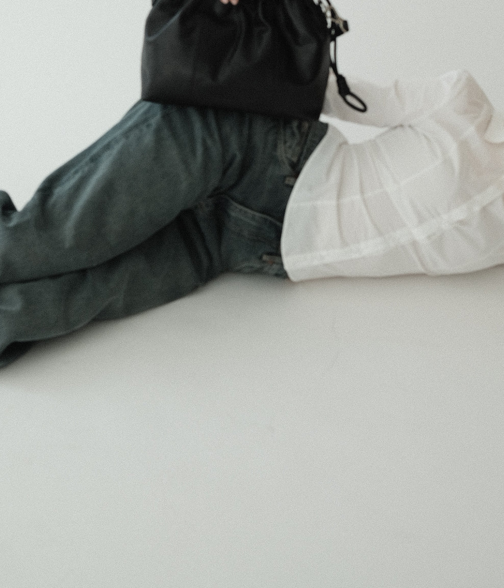 A small black Elliot leather handbag with a shoulder strap, displayed on a person lying down.