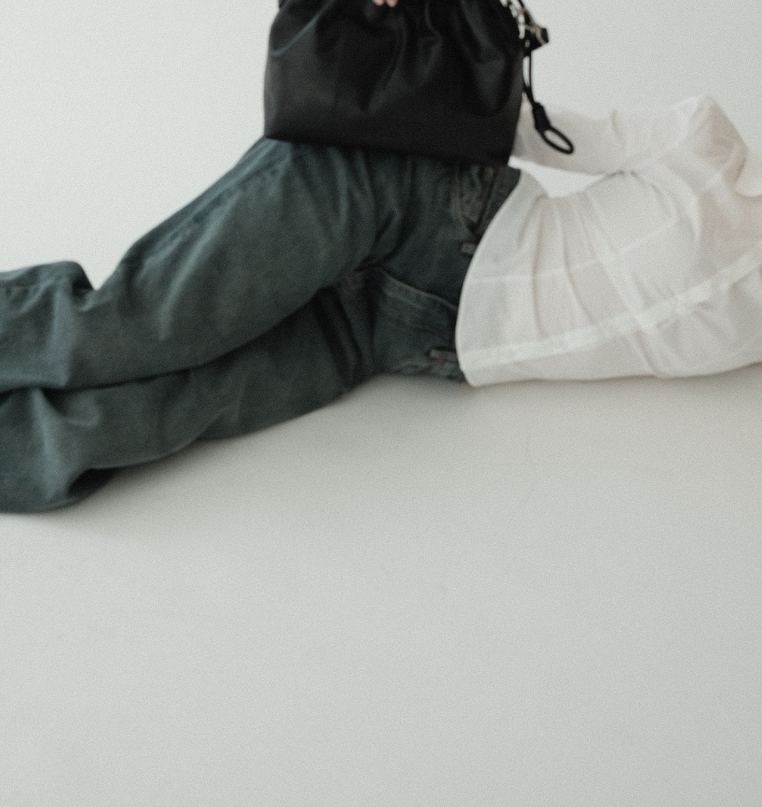 A small black Elliot leather handbag with a shoulder strap, displayed on a person lying down.