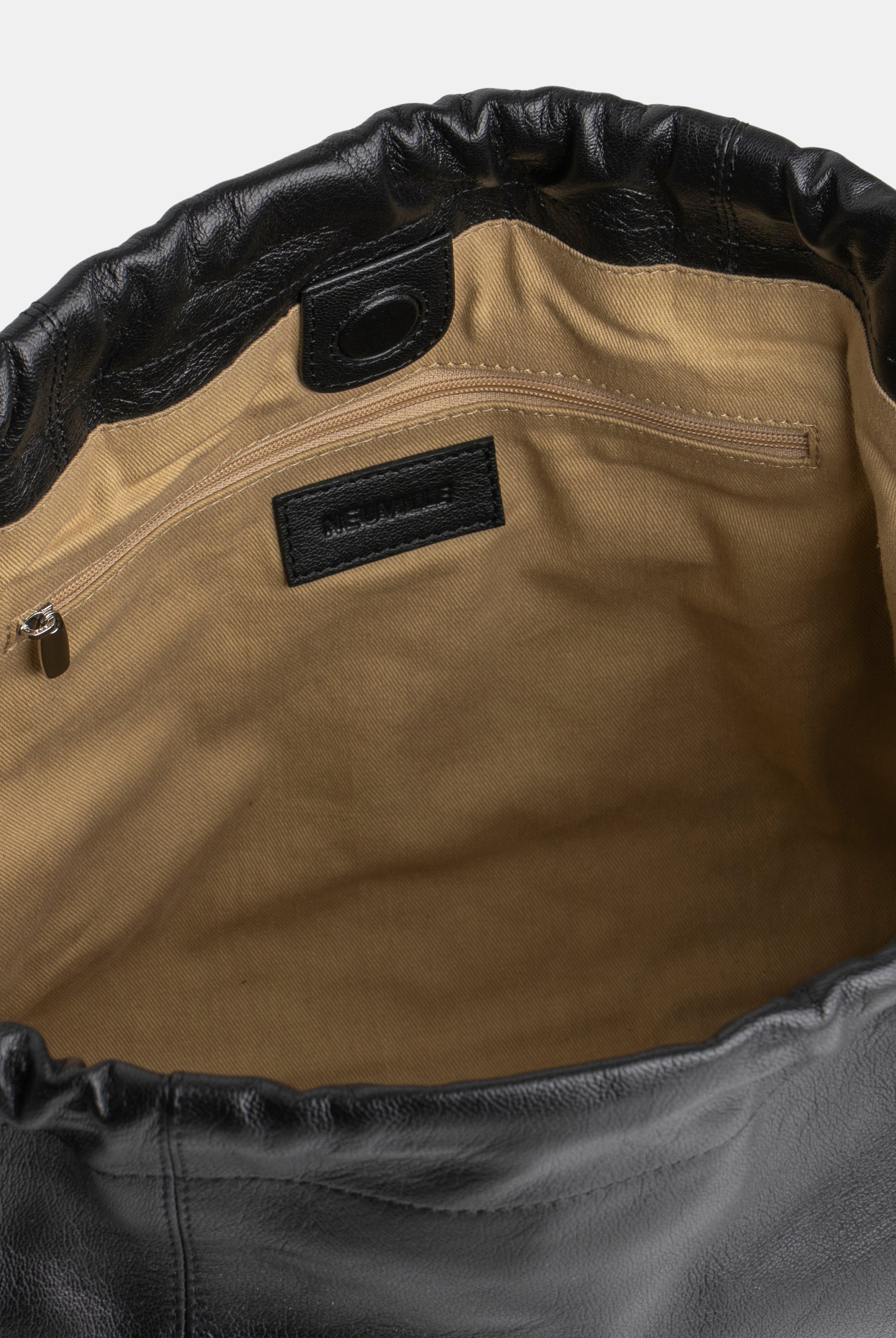 Close-up of a leather bag with a visible brand label on a white background