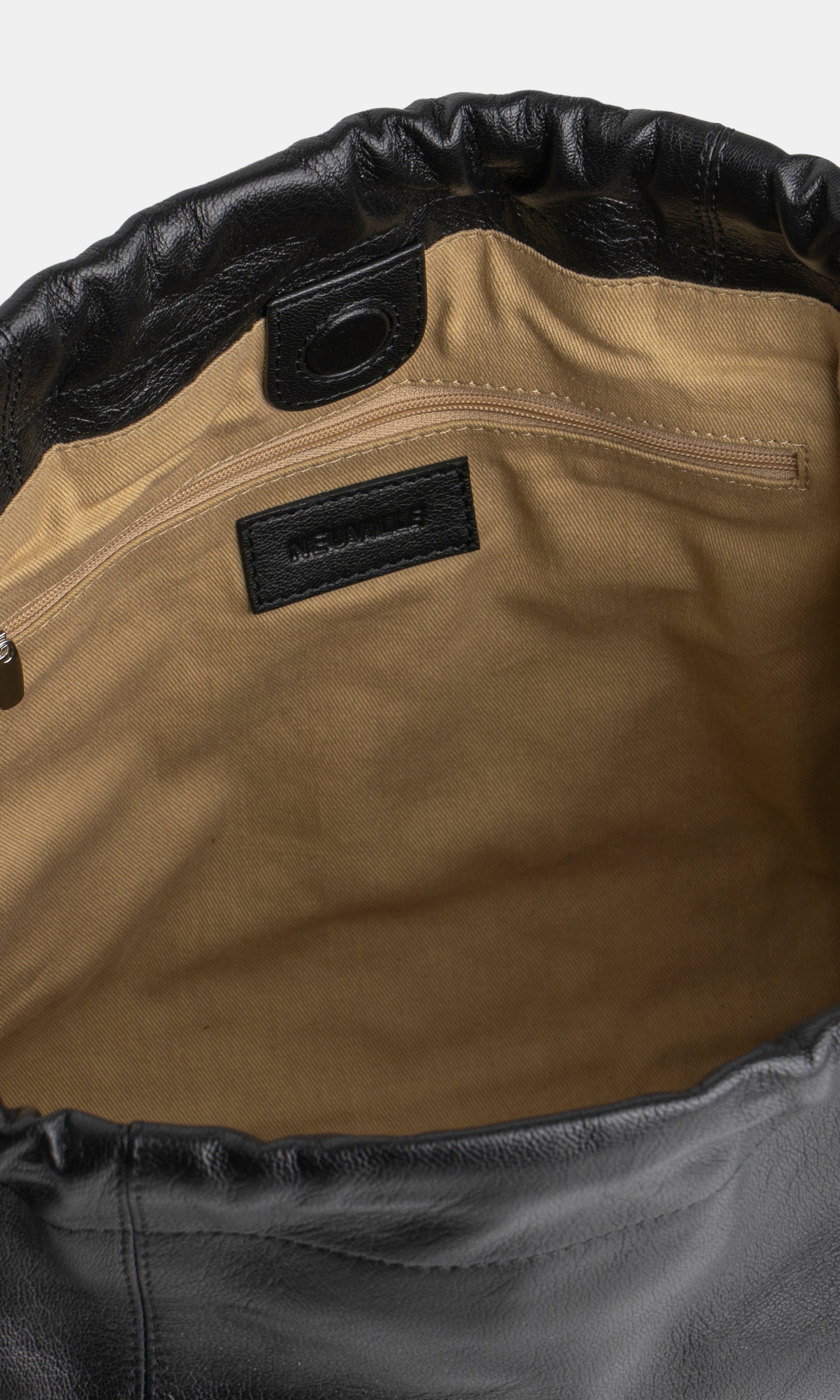 Close-up of a leather bag with a visible brand label on a white background