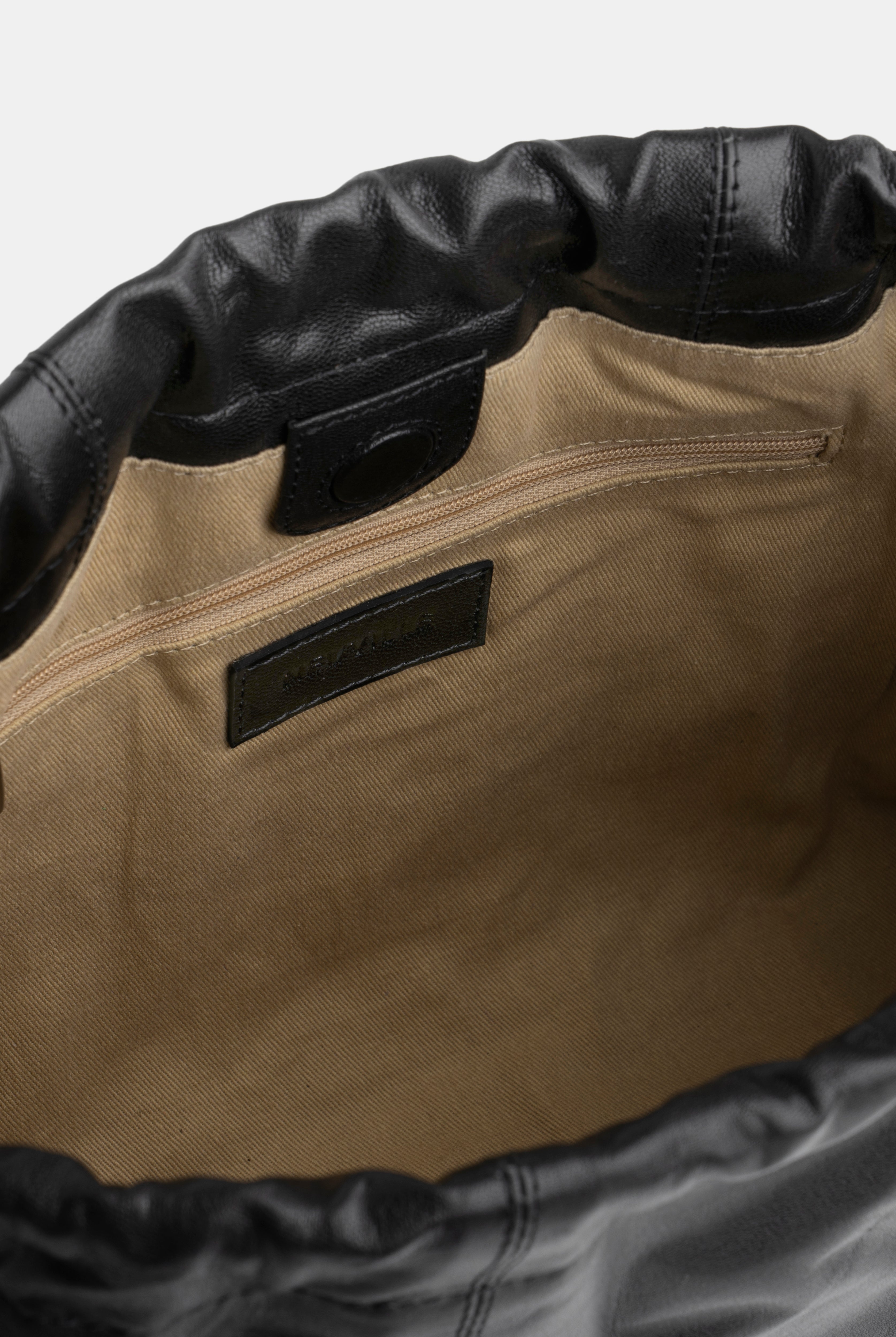 Close-up of a black bag with black leather trim and a visible brand label.