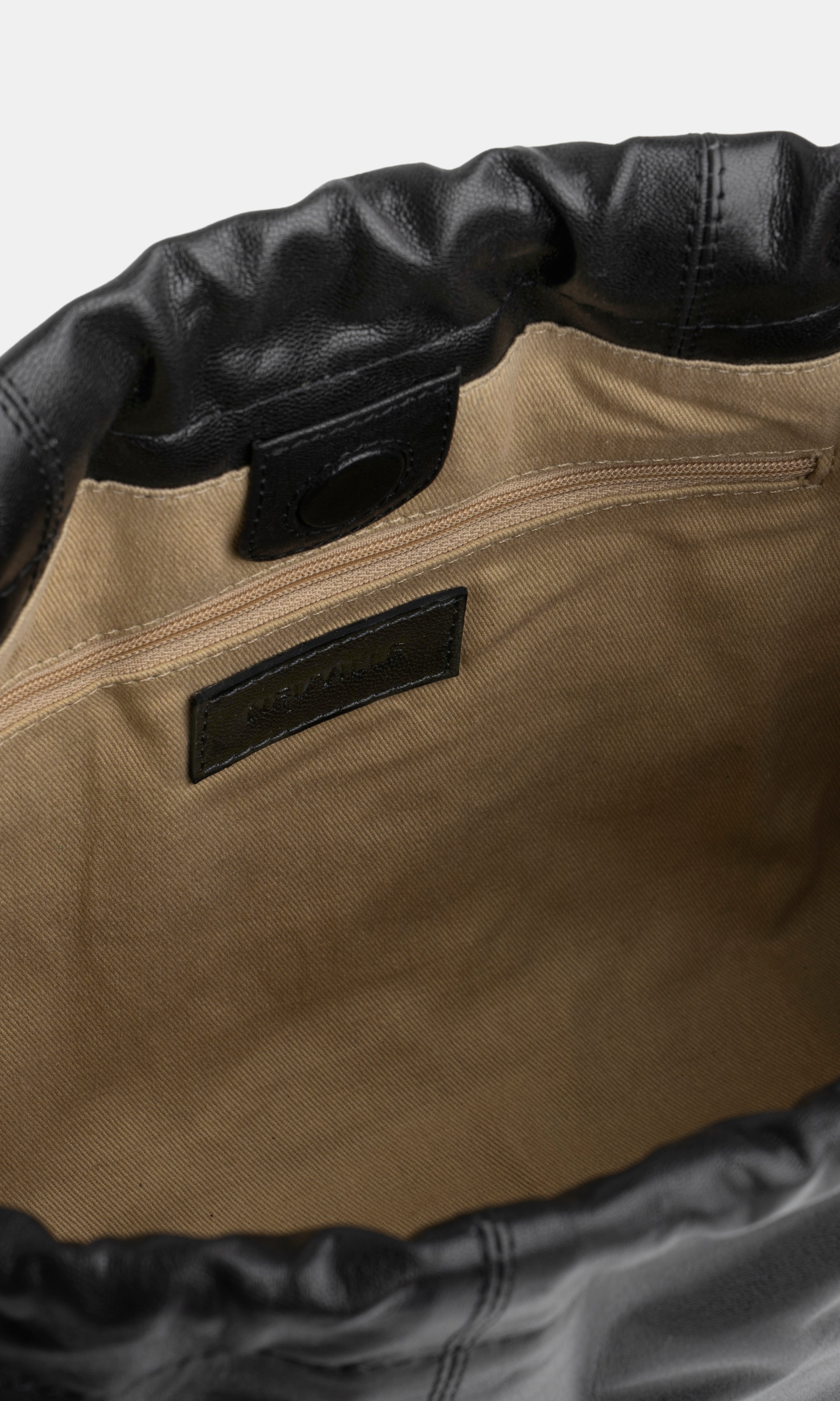 Close-up of a black bag with black leather trim and a visible brand label.