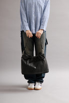 Girl wearing Elliot Black leather shoulder and crossbody bag of the brand Neuville in the studio