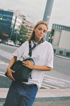 Girl wearing Elliot Black leather shoulder and crossbody bag of the brand Neuville in the street