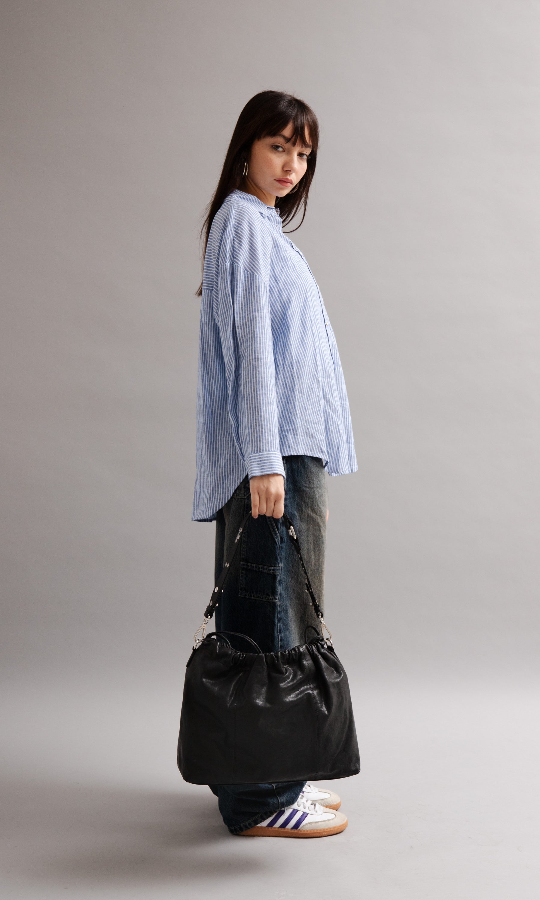 Girl wearing Elliot Black leather shoulder and crossbody bag of the brand Neuville in the street. side photo