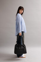 Girl wearing Elliot Black leather shoulder and crossbody bag of the brand Neuville in the street. side photo