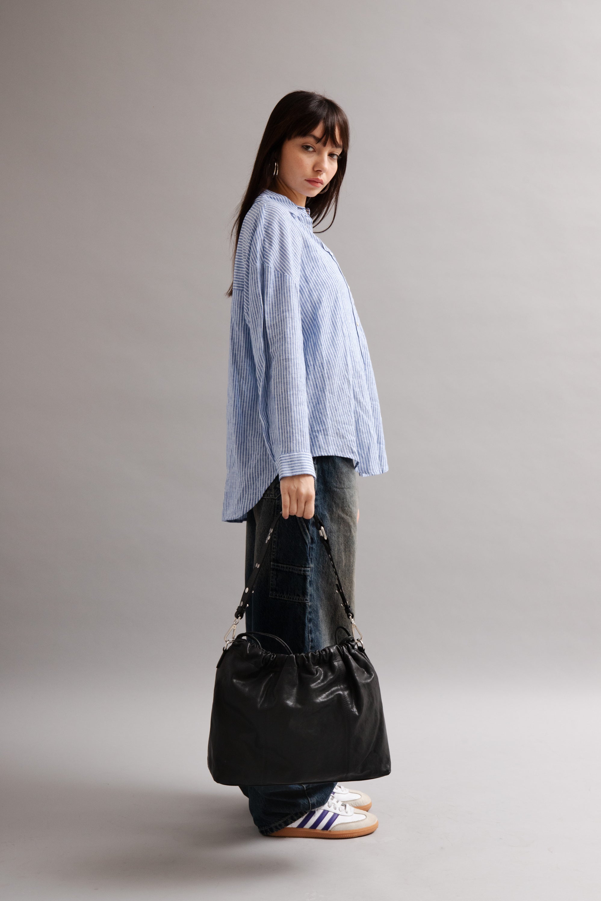 Girl wearing Elliot Black leather shoulder and crossbody bag of the brand Neuville in the street. side photo