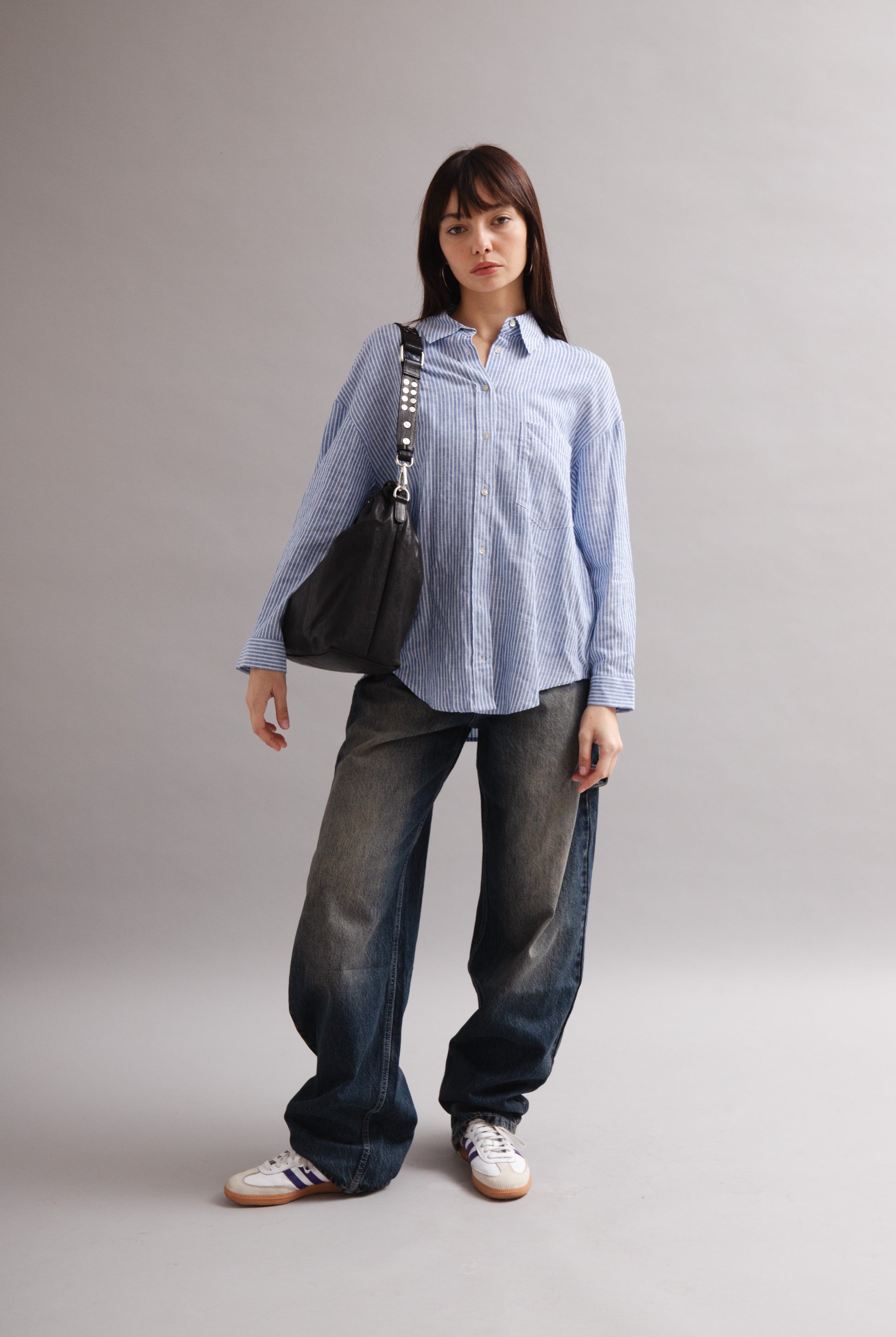 Girl wearing Elliot Black leather shoulder and crossbody bag of the brand Neuville in the studio. front photo
