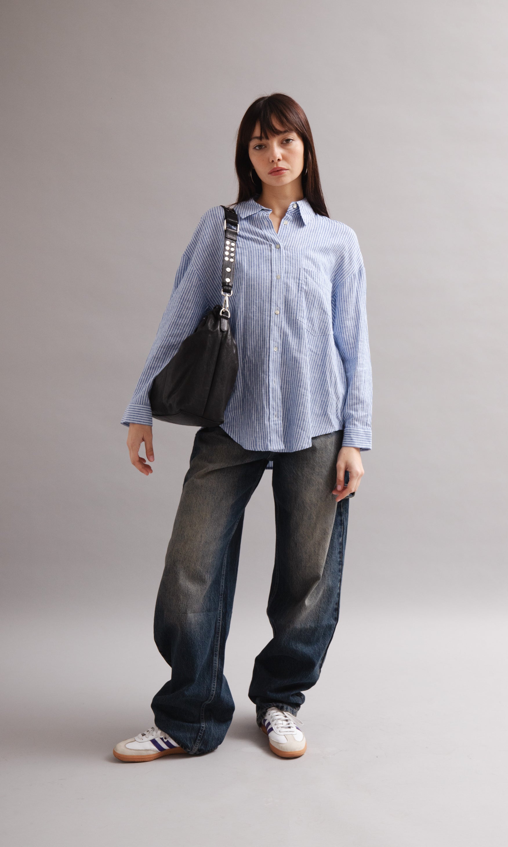 Girl wearing Elliot Black leather shoulder and crossbody bag of the brand Neuville in the studio. front photo