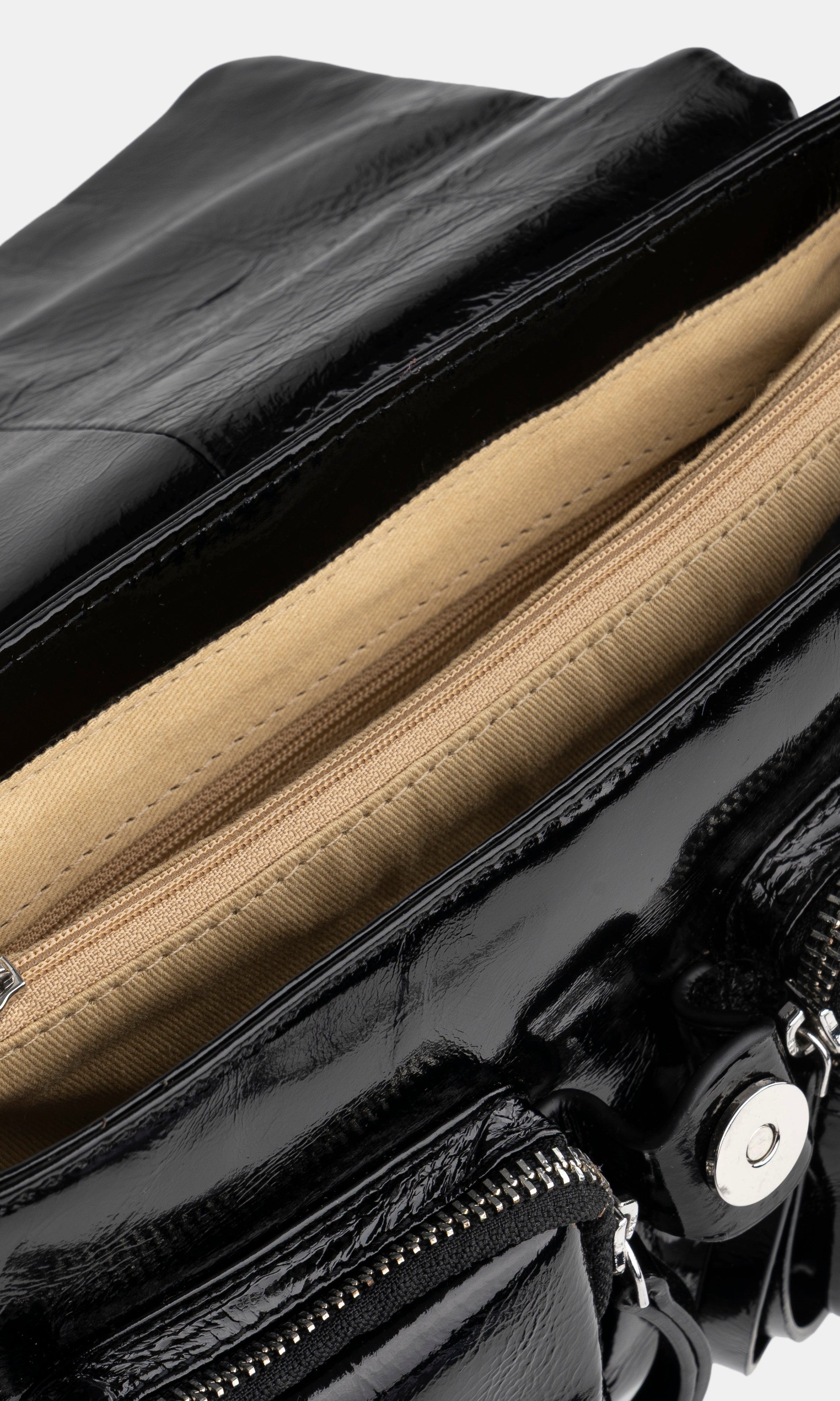Close-up of a black patent leather handbag with beige interior lining.