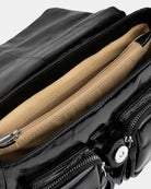 Close-up of a black patent leather handbag with beige interior lining.