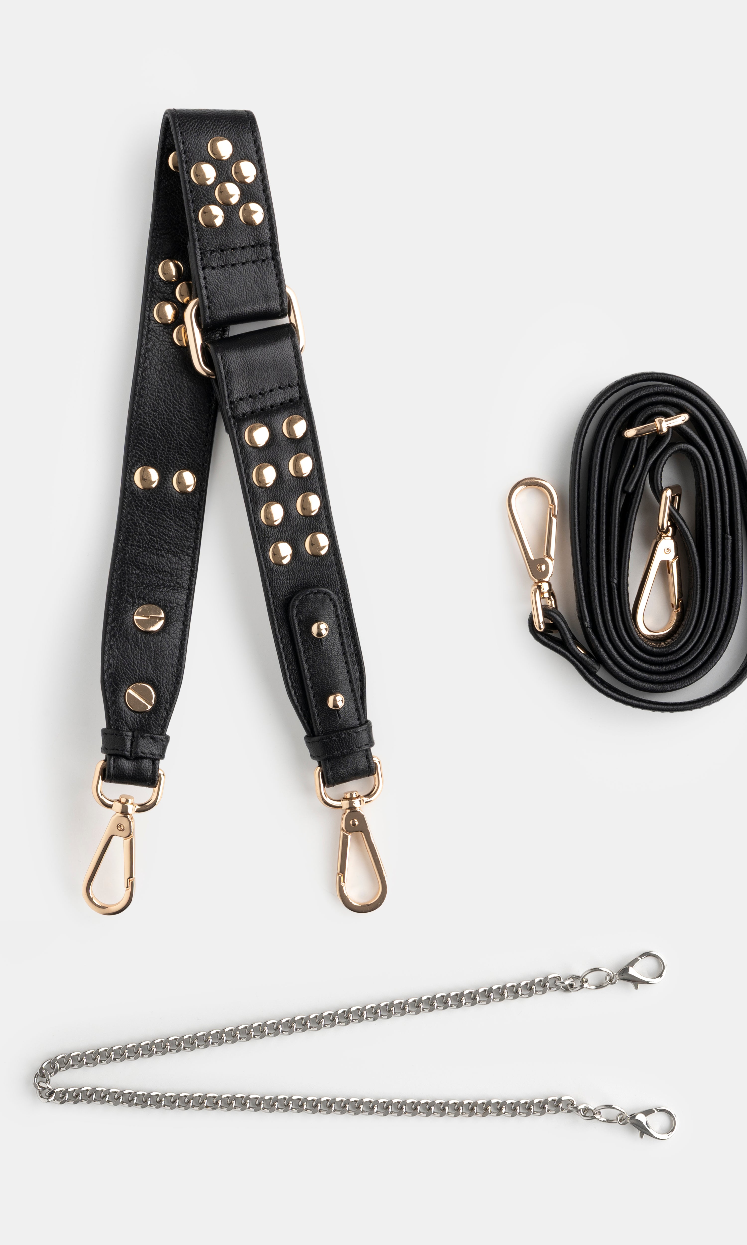 Black studded  shoulder bag strap with gold hardware and a black crossbody strap and a golden chain on a white background