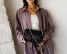 Person wearing a plaid shirt holding a black leather Maxke Black handbag
