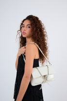 Woman holding a white handbag against a plain background