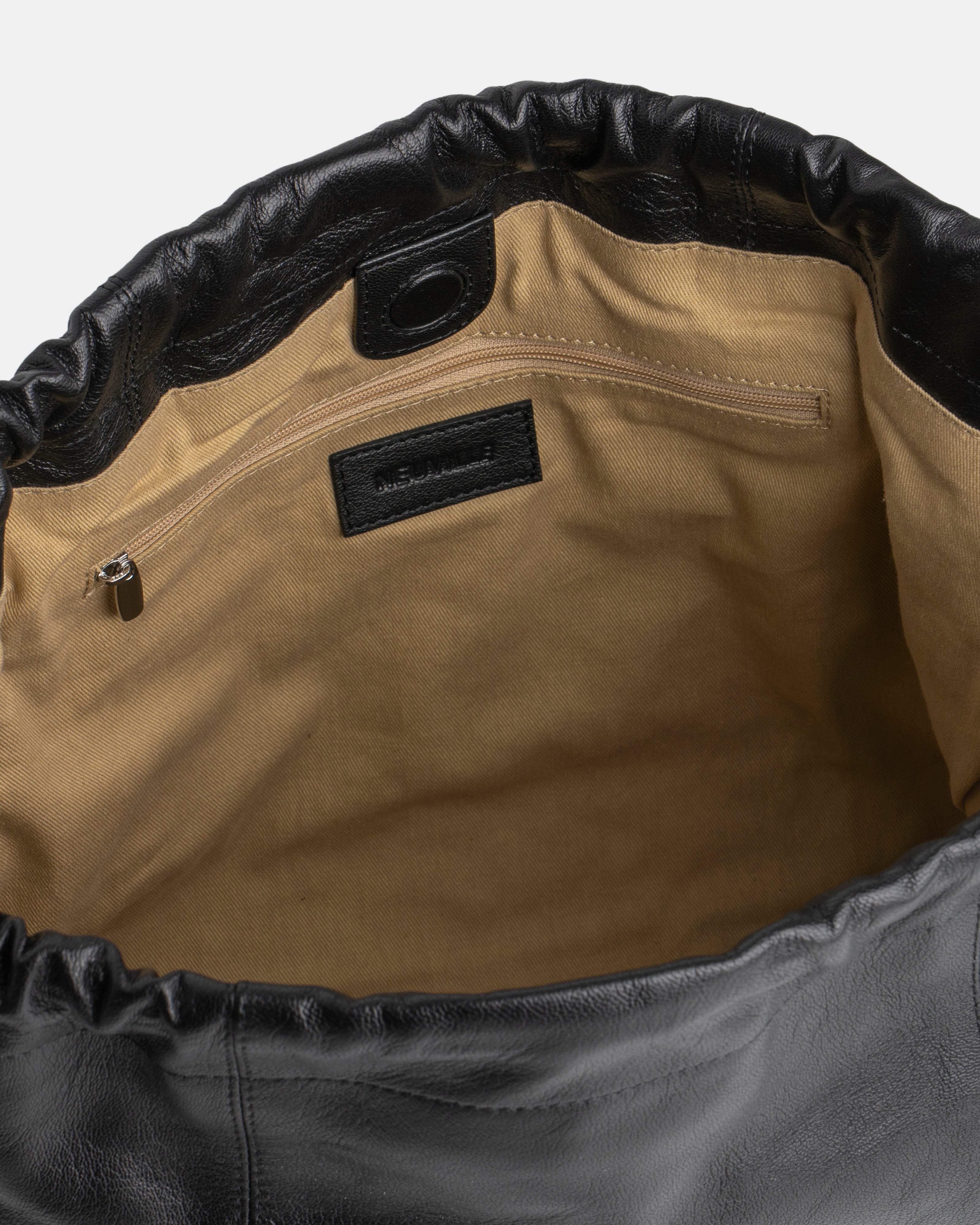 Close-up of a leather bag with a visible brand label on a white background