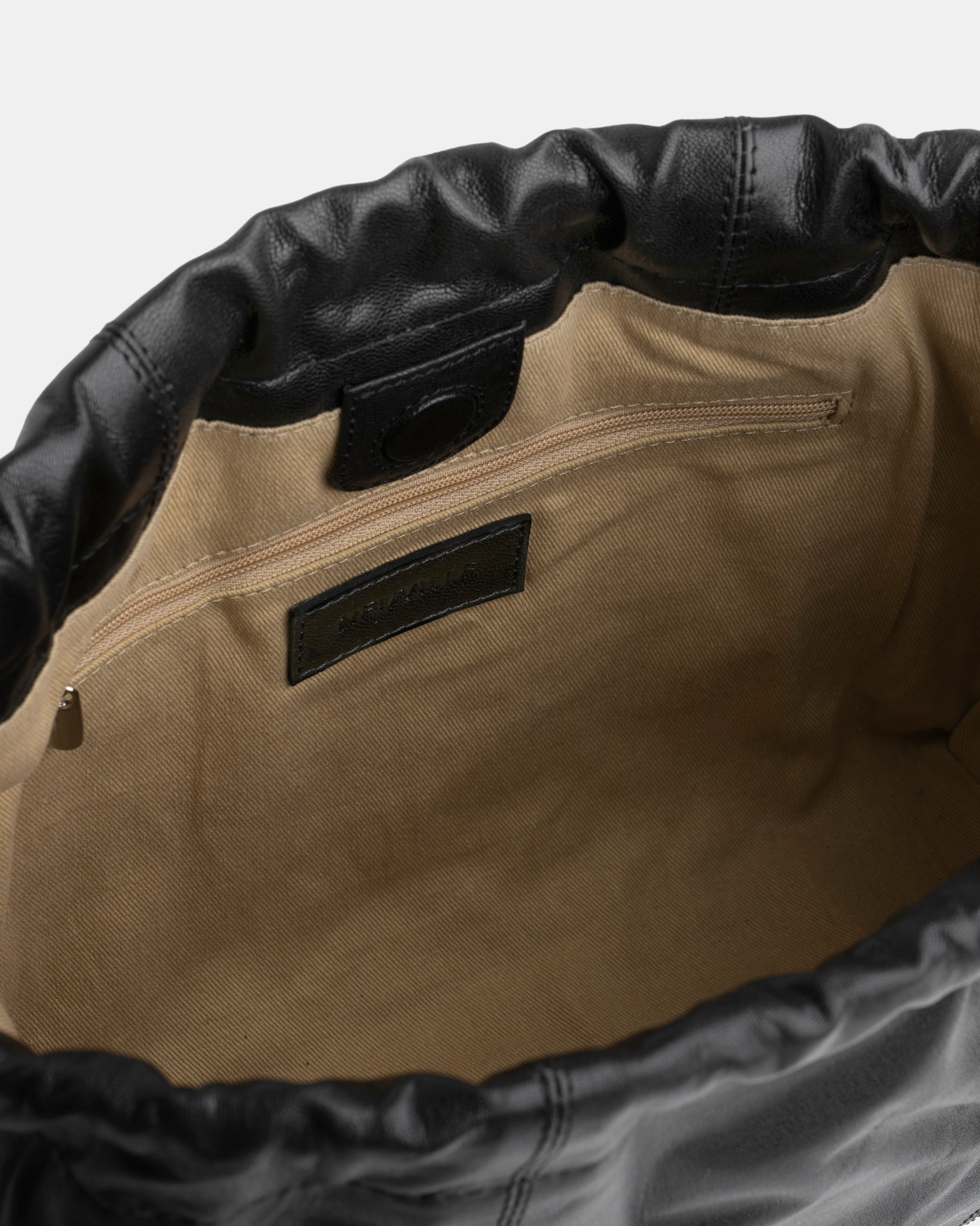 Close-up of a black bag with black leather trim and a visible brand label.