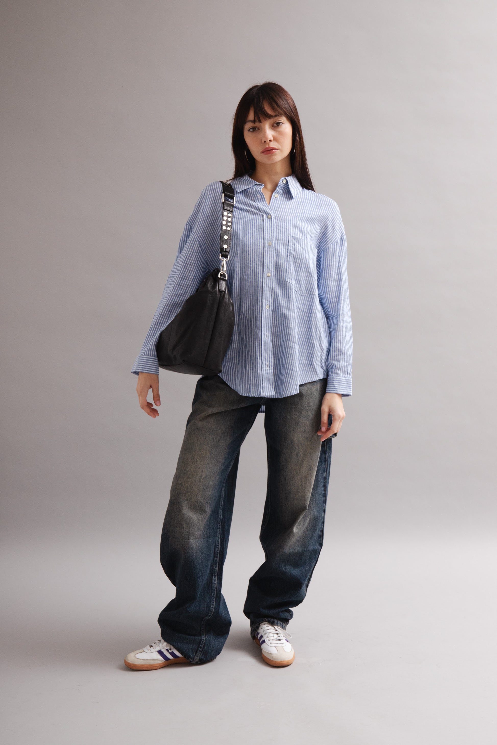 Girl wearing Elliot Black leather shoulder and crossbody bag of the brand Neuville in the studio. front photo