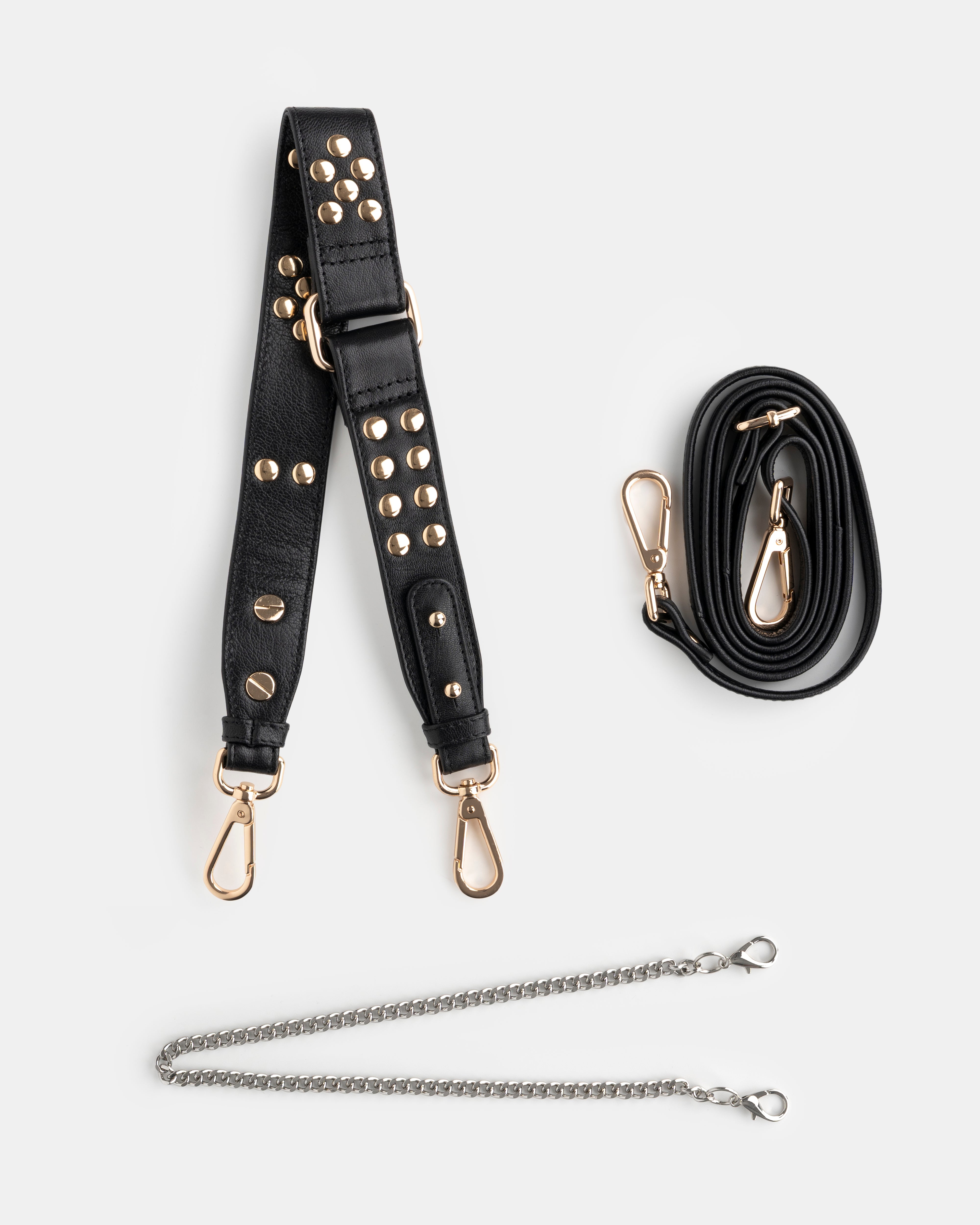 Black studded  shoulder bag strap with gold hardware and a black crossbody strap and a golden chain on a white background